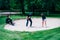 Golf sand bunker playing technique. Young woman practicing bunker shots with golf instructor