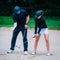 Golf sand bunker playing technique. Young woman practicing bunker shots with golf instructor