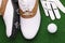 Golf shoes ball and white gloves lie on green lawn