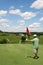 Golf - Son Putting Ball at Father Tending Flag