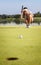 Golfer analyzing green for putting ball into cup.