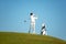 Golfer asia man approach on tee off for swing and hitting golf ball on slope green and looking fairway