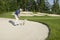 Golfer blasting out of bunker onto green