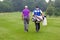 Golfer and caddy walking up a fairway