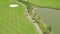 Golfer on green golf course top view from flying drone. Aerial view people on green field in golf club, car and lake