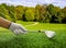 Golfer hand in glove holding a club, close up view. Golf course, blue sky background