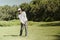Golfer hitting golf ball on fairway green grass