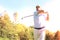 Golfer hitting golf shot with club on course while on summer vacation