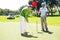 Golfer holding hole flag for friend putting ball