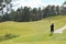 Golfer playing on a beautifully landscaped golf course with green grass, trees and blue sky background