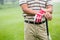 Golfer standing and leaning on his club