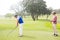 Golfer swinging his club with friend behind him