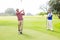 Golfer swinging his club with friend behind him