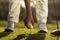 Golfers hand placing golf ball onto tee close up with blurred feet and flare background