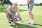 Golfing couple on the putting green with man smiling at camera