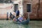 A gondola with cheerful tourists on the Venetian channel
