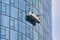 Gondola with workers cleaning the windows on the mirroring smooth shining outer wall of the Main Tower