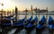 Gondolas anchored at pier of San Marco square at sunrise on Grand Canal towards San Giorgio Maggiore, Venice, Italy.