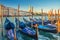 Gondolas moored docked on pier of Grand Canal waterway in Venice