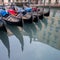 Gondolas parked on a canal in Venice, Italy showing the decorative ferro / iron at the bow of the boats and the risso