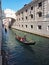 A gondolier ferries passengers in a gondola on the canals of Venice