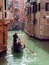 Gondolier floats on the narrow channel in Venice, Italy