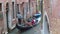 Gondolier on his gondola kicks off the building and rides tourists, Venice