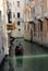 Gondolier rides gondola in a narrow channel, Venice, Italy