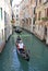 Gondolier rides gondola in a narrow channel, Venice, Italy