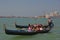 Gondolier rowing oar for tourist gondola in Venice gliding through the Venetian canal with them taking pictures & posing
