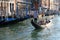 Gondolier takes tourists on his gondola on Grand Canal by moored gondolas. Venice, Italy. Venice during coronavirus