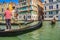 Gondolier and tourists on gondola traditional boat sailing on water of Grand Canal in Venice