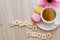 Good afternoon message coffee break concept  white cup of frothy espresso coffee with colourful French macaroons on wooden