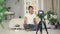 Good-looking African American girl creative blogger is recording video about plants sitting on floor of her apartment