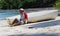 Good looking castaway man sitting in the beach by a wrecked boat waiting for help with ocean and jungle in the background.