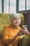 Good-looking elderly lady in yellow typing a message