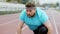 Good looking fat man in the sports outfit at starting line he getting ready for a hard workout in the stadium outside