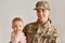 Good looking happy positive young adult woman soldier posing with her infant daughter, expressing happiness returning home from