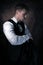 Good looking man with beard, curly hair wearing waistcoat and bowtie pulling on his jacket, looking away from camera