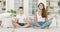 Good-looking positive balanced young woman and her 8-aged son which meditating on soft white sofa in living-room