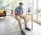 A good looking senior man sitting with his painting in frame on a tripod with happiness manner as an older hobby