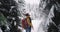 Good looking young man tourist traveling in amazing snowy forest with a big snowy tree he walking through the snow with