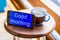 good morning digital text in blue smartphone screen with a glass of tea on brown wooden table