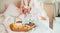 Good morning mood. Young woman in bathrobe sitting on the bed, drinking coffee and has her breakfast in bed with Have a nice day