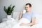 Good morning, relaxation and happiness concept - handsome man sitting in bed and drinking coffee