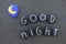 Good night message with a composition of black painted stones over black volcanic sand