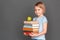 Good student. Little girl isolated on grey with pile of books and apple smiling modest