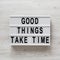 `Good things take time` words on a lightbox on a white wooden background, top view. Overhead, from above, flat lay. Close-up