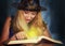 Good witch in the hat reads magic spells in the book on the fog background