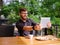 Goodly young man working on tablet while sitting outdoors . Business concept.